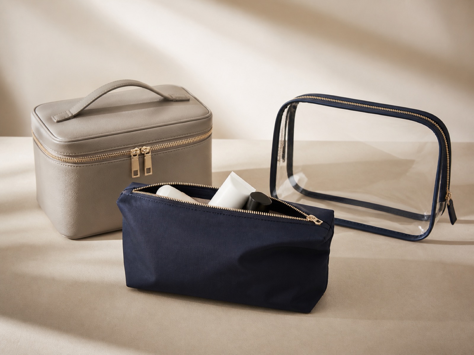 Private-label cosmetic pouches in several colours with logo samples and a tech pack on a design table