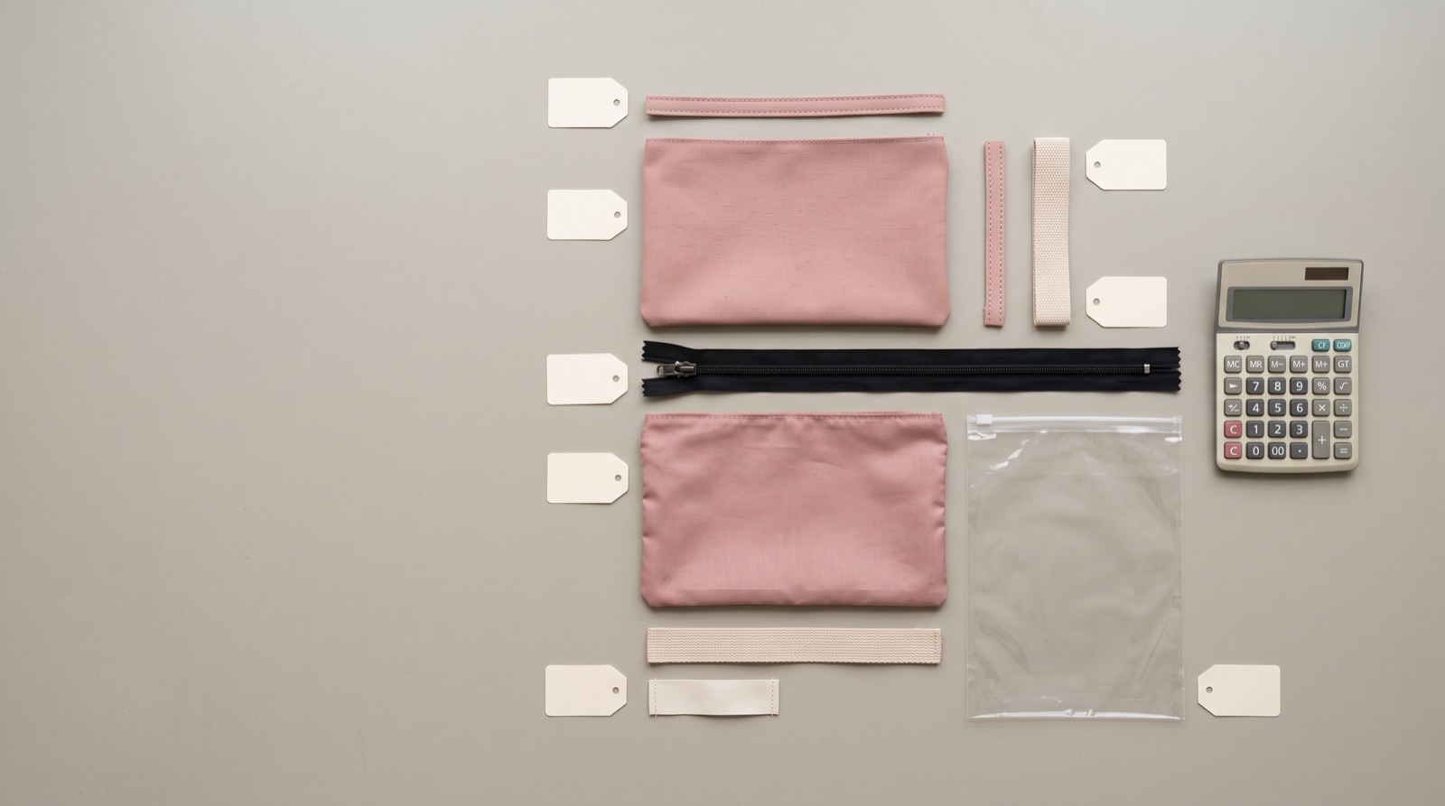 Pattern pieces, zipper tape and trim laid out on a cutting table during costing of a custom cosmetic bag